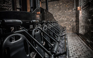 Edinburgh Dungeon ride seats lined up against stone wall.
