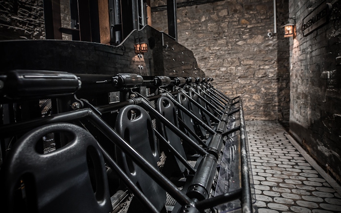 Edinburgh Dungeon ride seats lined up against stone wall.