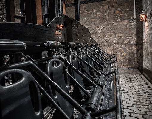Edinburgh Dungeon ride seats lined up against stone wall.