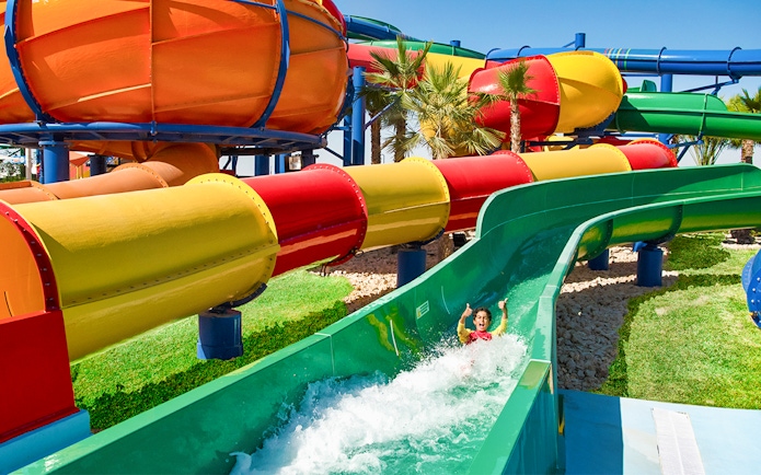 Child enjoying a water slide at LEGOLAND® Water Park with colorful tubes in the background.