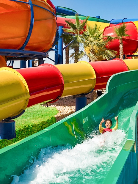 Child enjoying a water slide at LEGOLAND® Water Park with colorful tubes in the background.