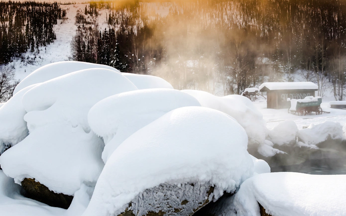 Snow-covered rocks and steaming hot springs at Chena Hot Springs, Alaska.