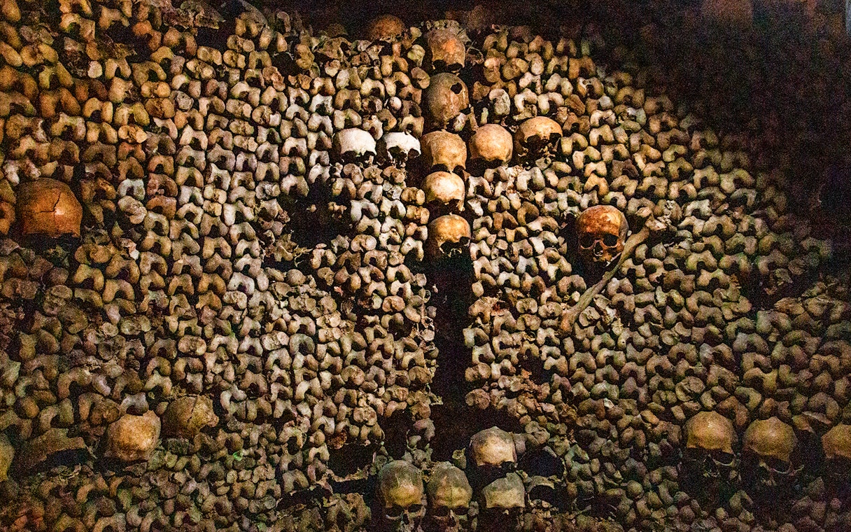 Skulls and bones arranged in the Paris Catacombs during a guided tour.