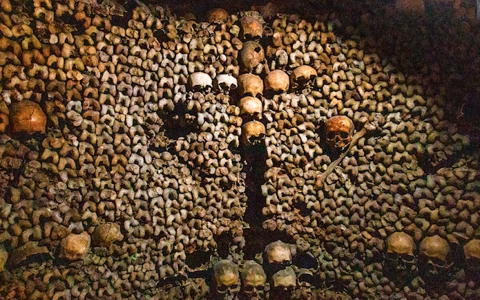 Skulls and bones arranged in the Paris Catacombs during a guided tour.