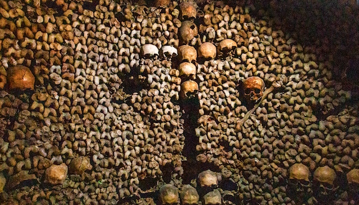 Skulls and bones arranged in the Paris Catacombs during a guided tour.