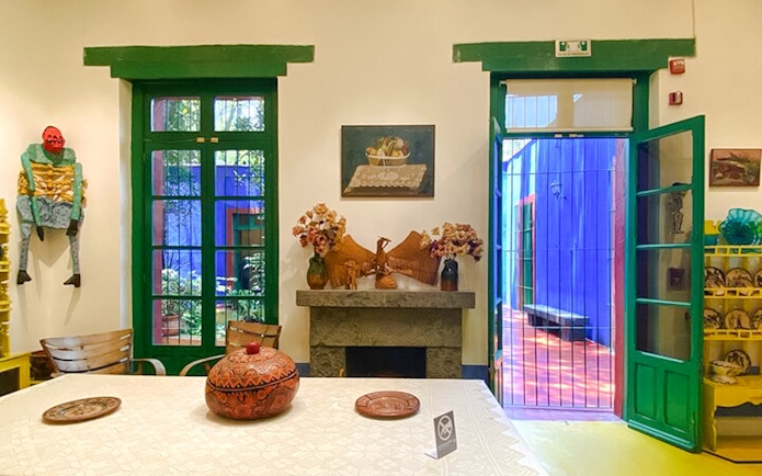 Frida Kahlo Museum interior with vibrant decor and open doors to colorful courtyard.