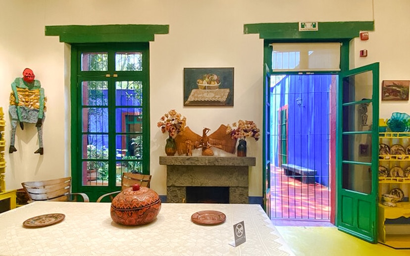 Frida Kahlo Museum interior with vibrant decor and open doors to colorful courtyard.