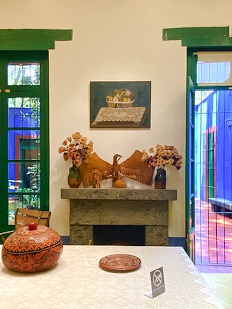 Frida Kahlo Museum interior with vibrant decor and open doors to colorful courtyard.