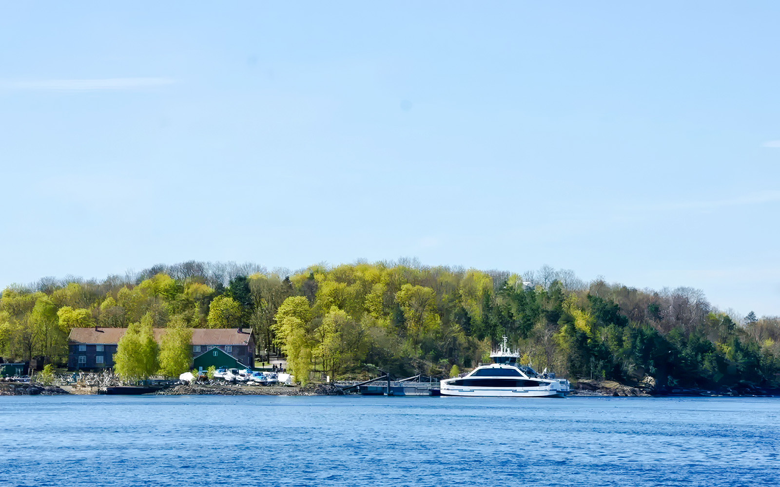 Ferry docked at an island with lush trees during Oslofjord Island Hopping Tour.