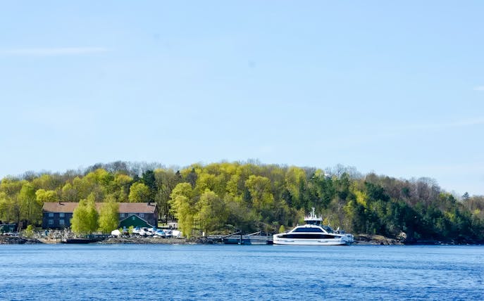 Ferry docked at an island with lush trees during Oslofjord Island Hopping Tour.