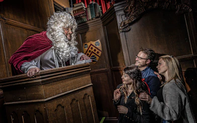 Judge in period costume engaging with visitors at York Dungeon courtroom.