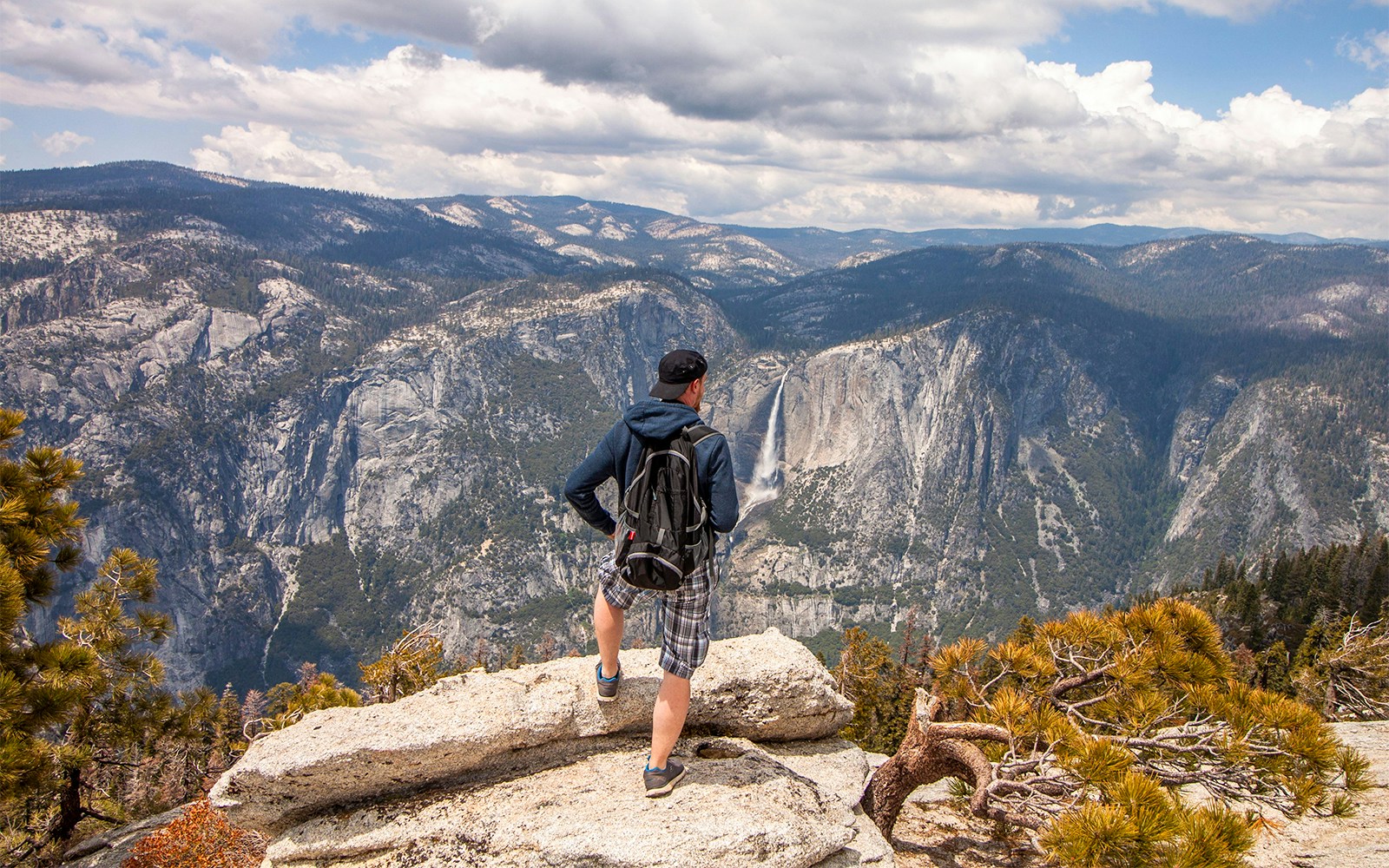 Hiker overlooking mountains and waterfall on Franz Josef Sentinel Rock walk.