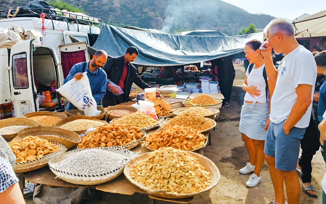 Market stall with local snacks and tourists in Ourika Valley, Morocco.
