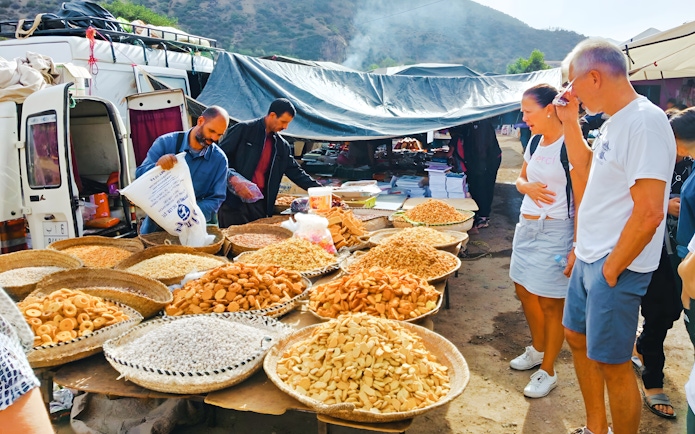Market stall with local snacks and tourists in Ourika Valley, Morocco.