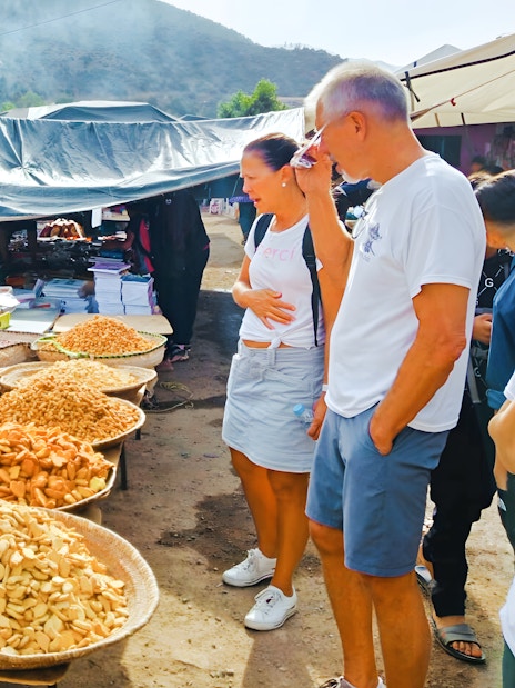Market stall with local snacks and tourists in Ourika Valley, Morocco.