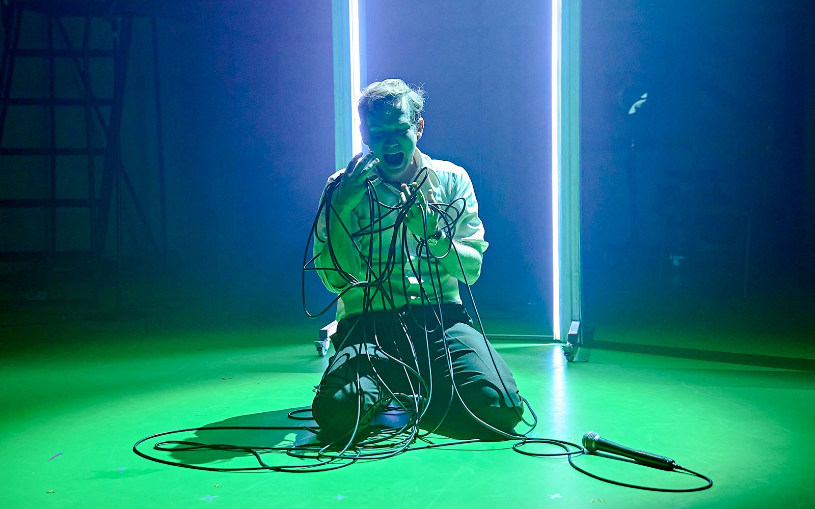 Performer kneeling on stage with cables, Kenrex stage performance.