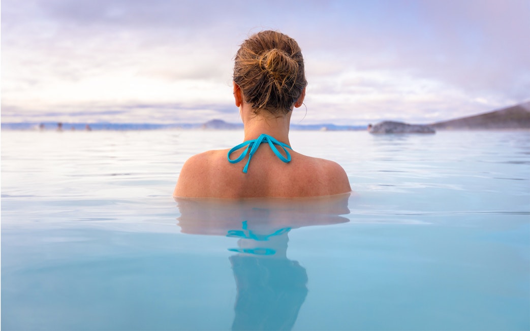 Person relaxing in Myvatn Nature Baths, Iceland, surrounded by geothermal waters.