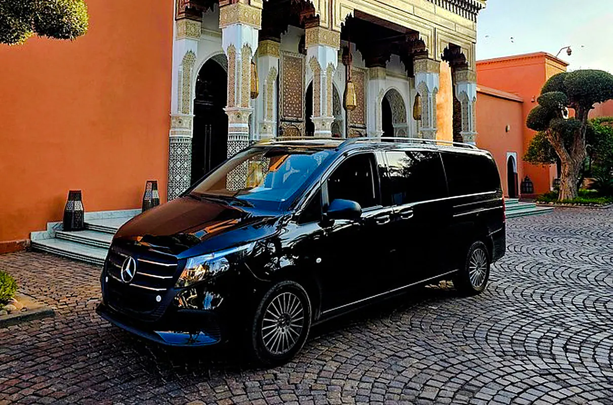 Black Mercedes van parked outside traditional Moroccan building, Marrakech transfer service.