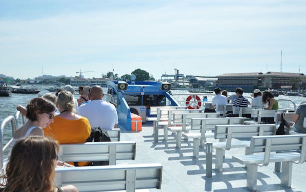 Passengers seated on a boat cruising the Chao Phraya River in Bangkok.