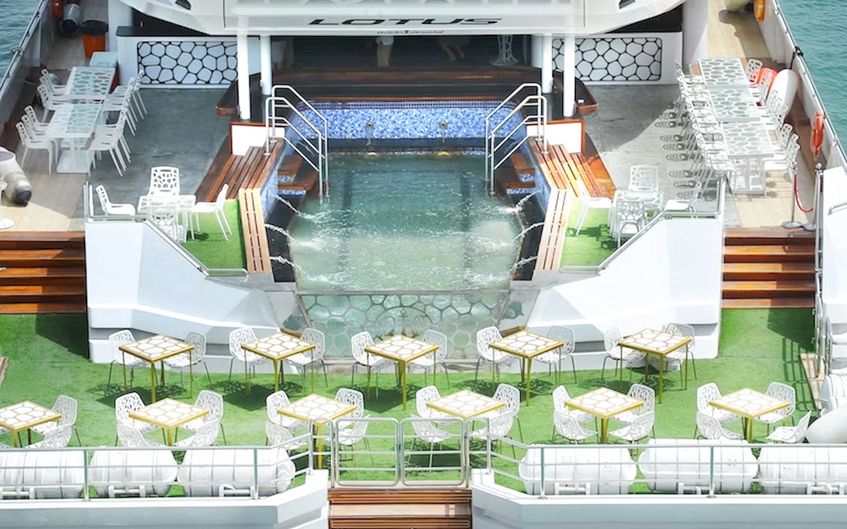 Lotus Mega Yacht deck with dining tables and pool, Dubai Marina cruise.