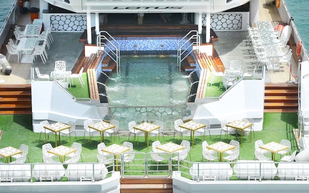 Lotus Mega Yacht deck with dining tables and pool, Dubai Marina cruise.