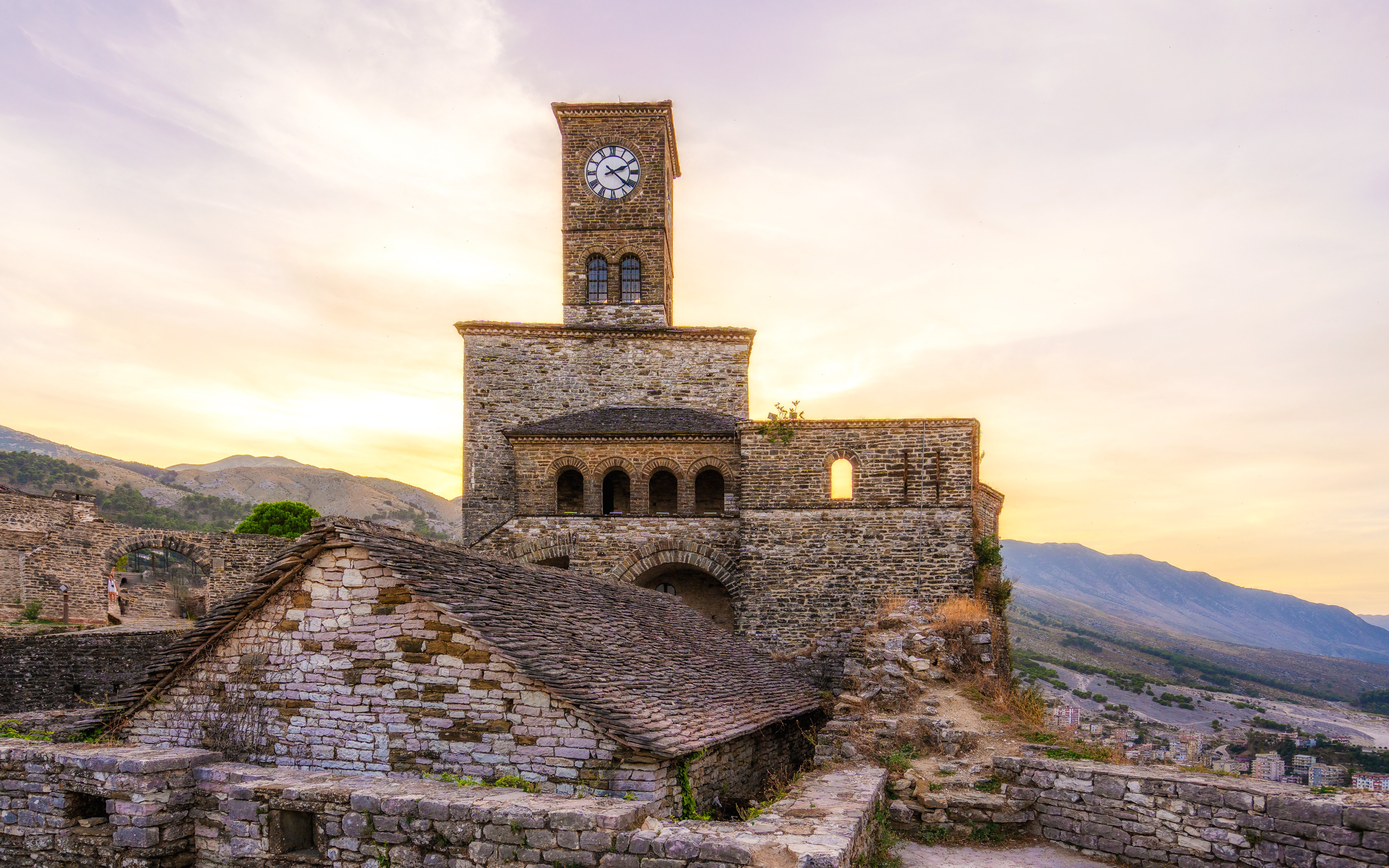 Gjirokastra Castle at sunset with clock tower and stone walls, Albania.
