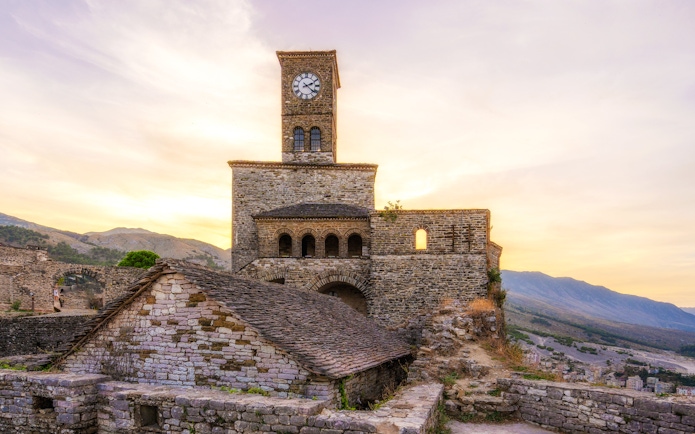 Gjirokastra Castle at sunset with clock tower and stone walls, Albania.