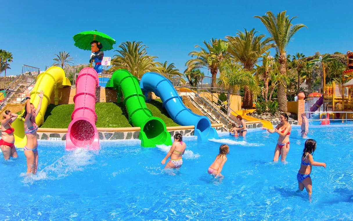 Children playing near colorful water slides at Aqualand Maspalomas.