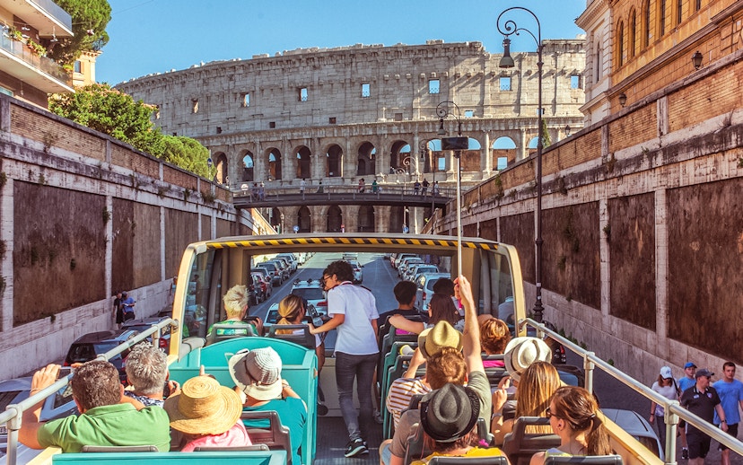 Tour guide interacting with tourists on a bus near the Colosseum in Rome.