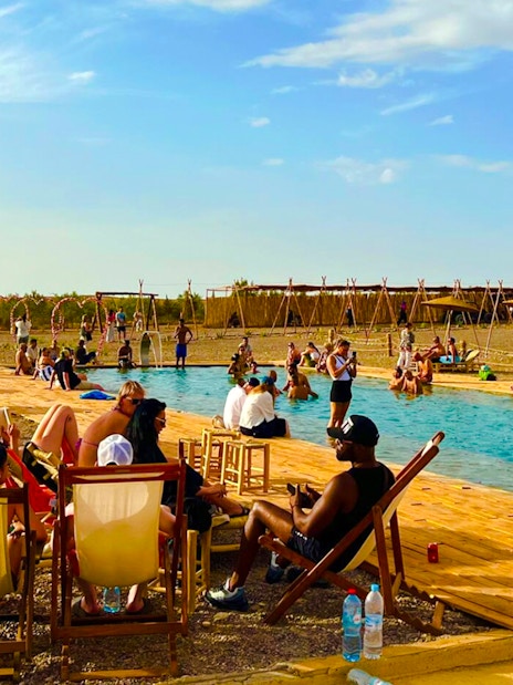 People relaxing by a pool in Agafay Desert, Marrakesh.