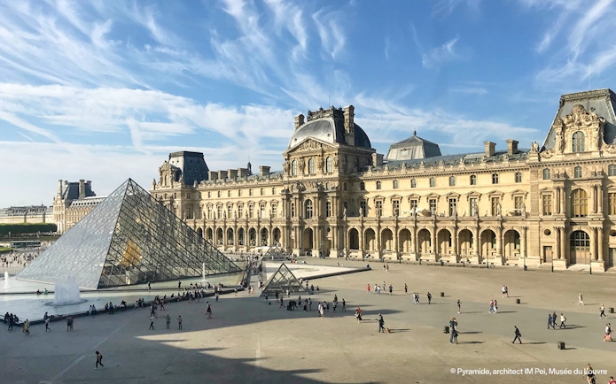 People walking near the Louvre glass pyramid in Paris, France.
