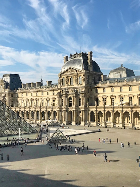 People walking near the Louvre glass pyramid in Paris, France.
