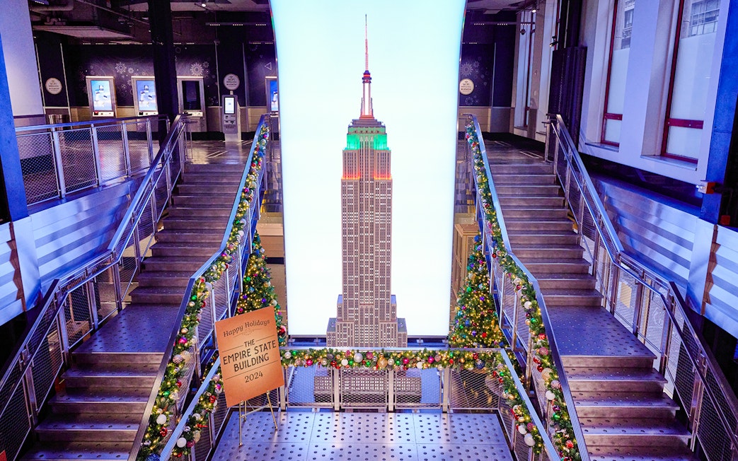 Empire State Building interior with Christmas decorations and model display.