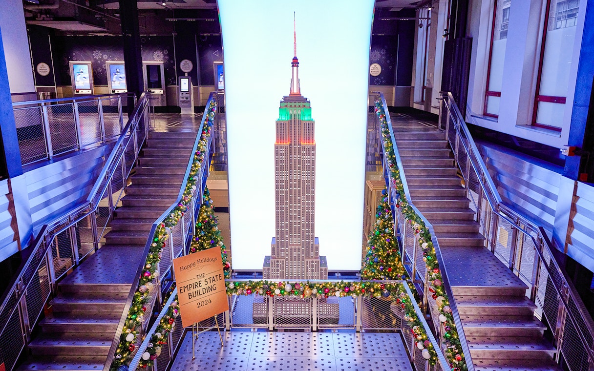 Empire State Building interior with Christmas decorations and model display.