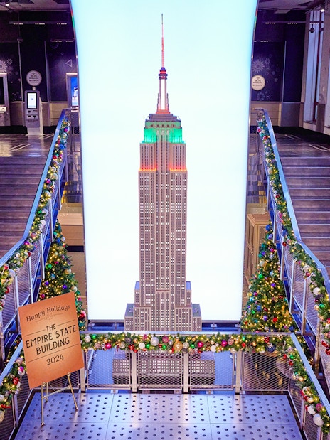 Empire State Building interior with Christmas decorations and model display.