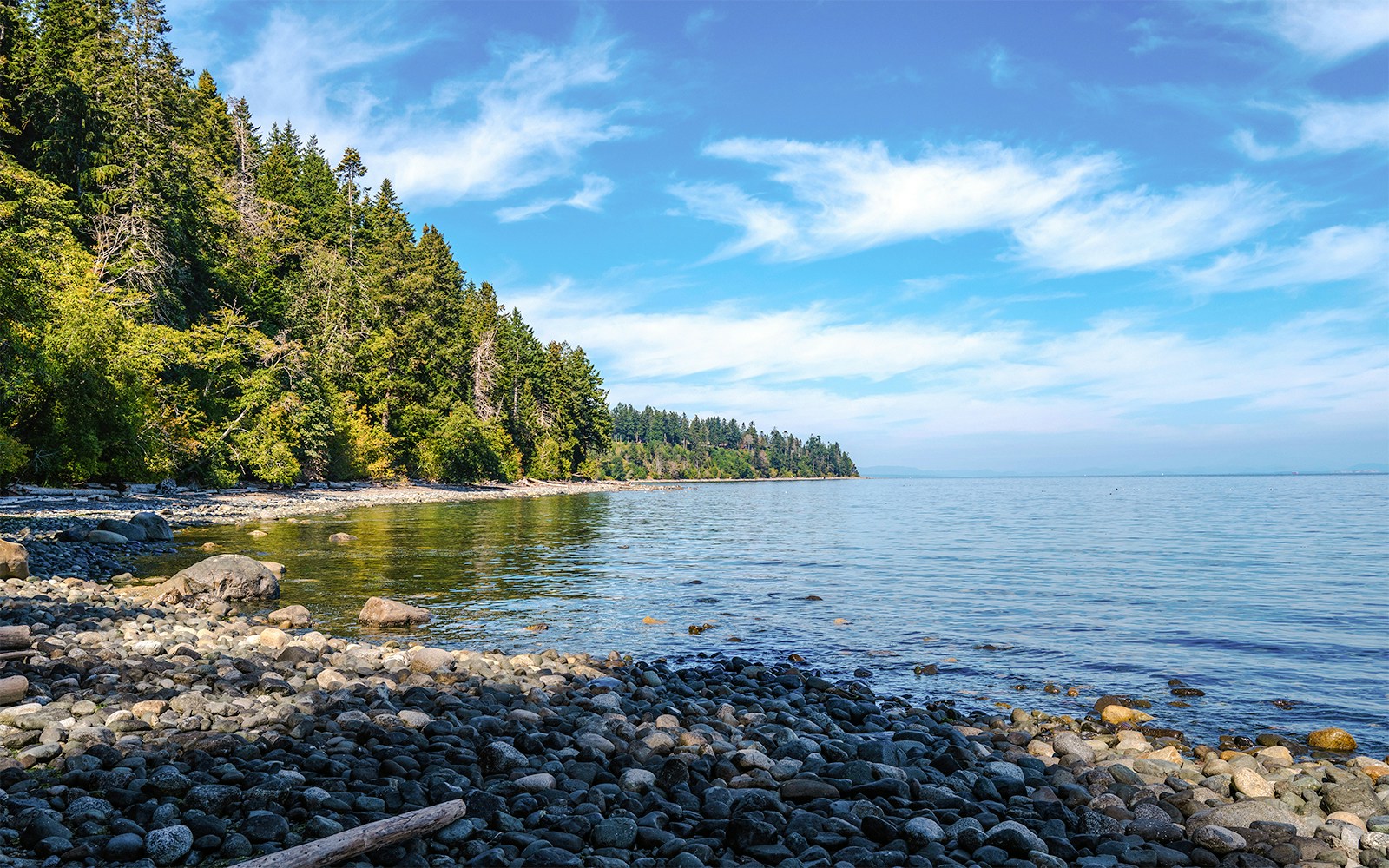 Rocky beach on Vancouver Island with view of Strait of Georgia and forested shoreline.