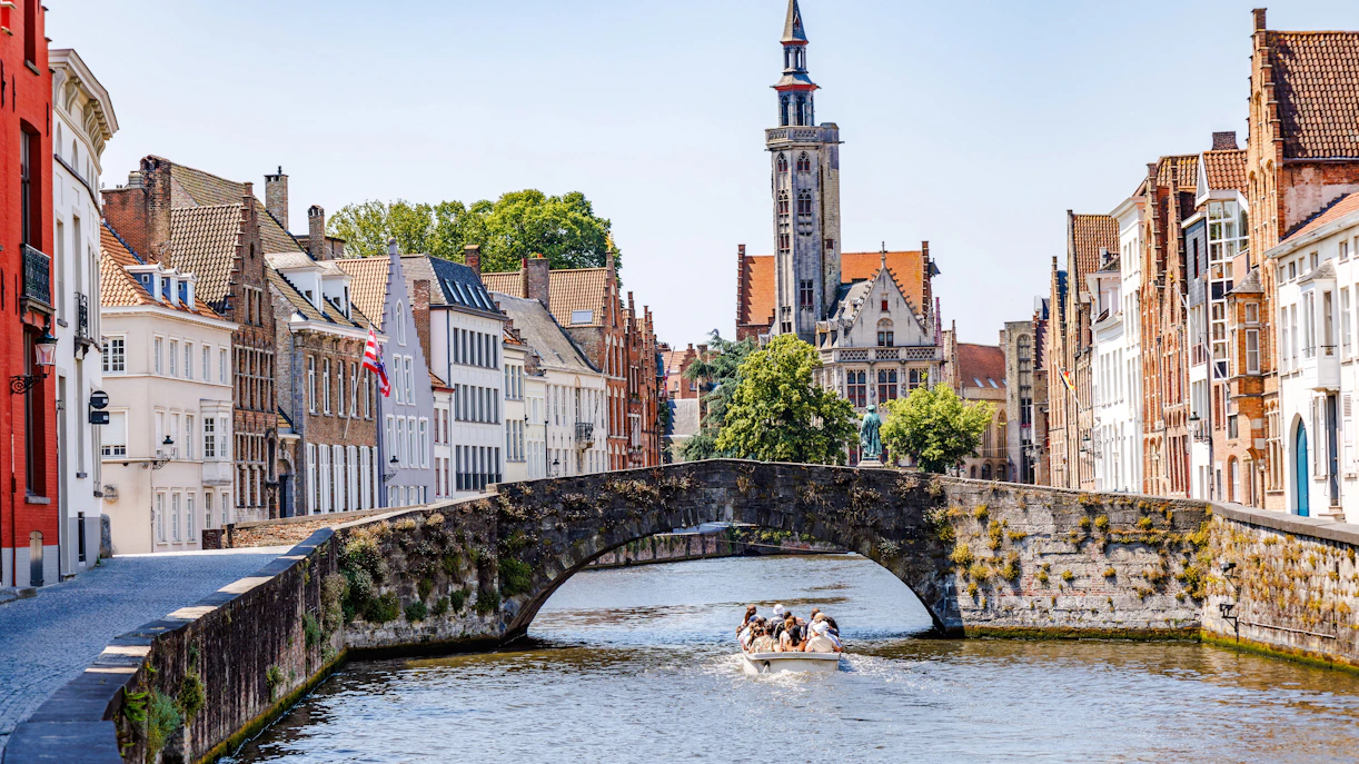 Stone bridge over Langerei Canal in Bruges with boat and historic buildings.