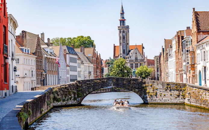 Stone bridge over Langerei Canal in Bruges with boat and historic buildings.