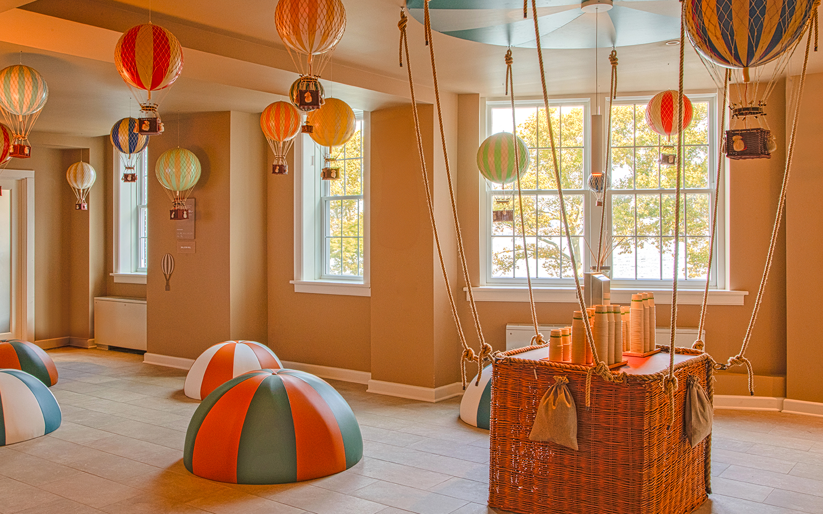 Hot air balloon-themed room at QC New York with colorful decorations and wicker basket.