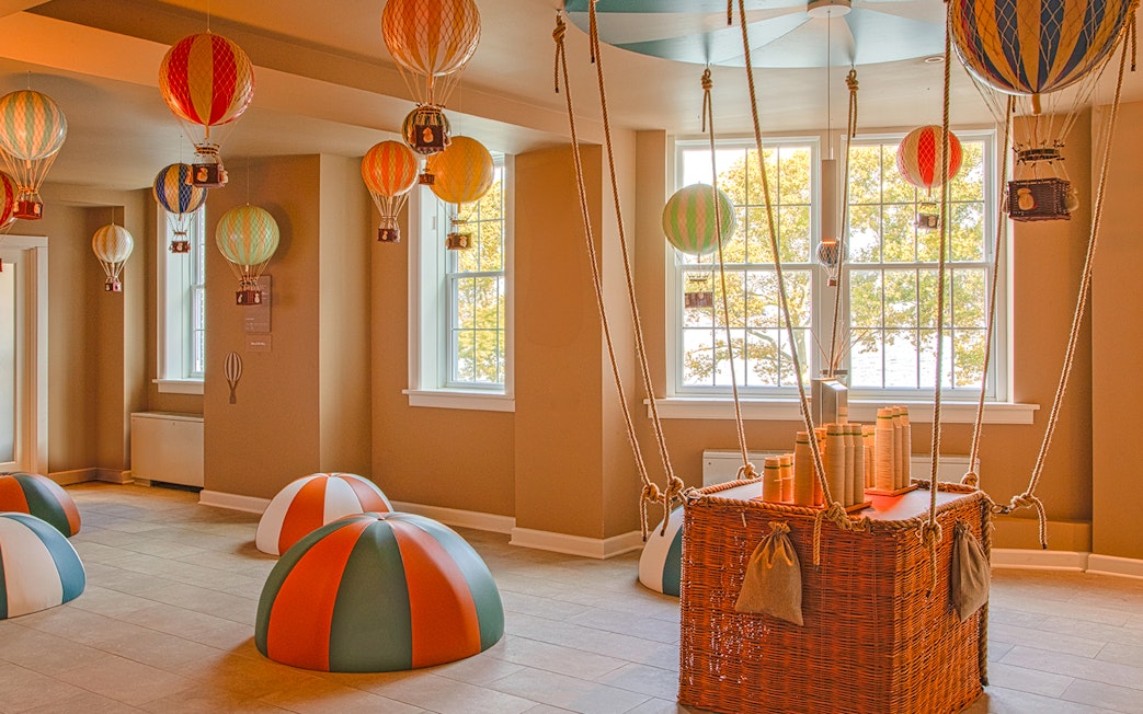 Hot air balloon-themed room at QC New York with colorful decorations and wicker basket.