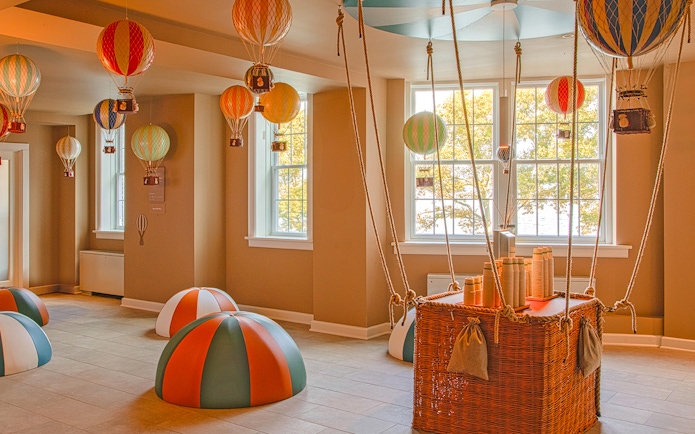 Hot air balloon-themed room at QC New York with colorful decorations and wicker basket.