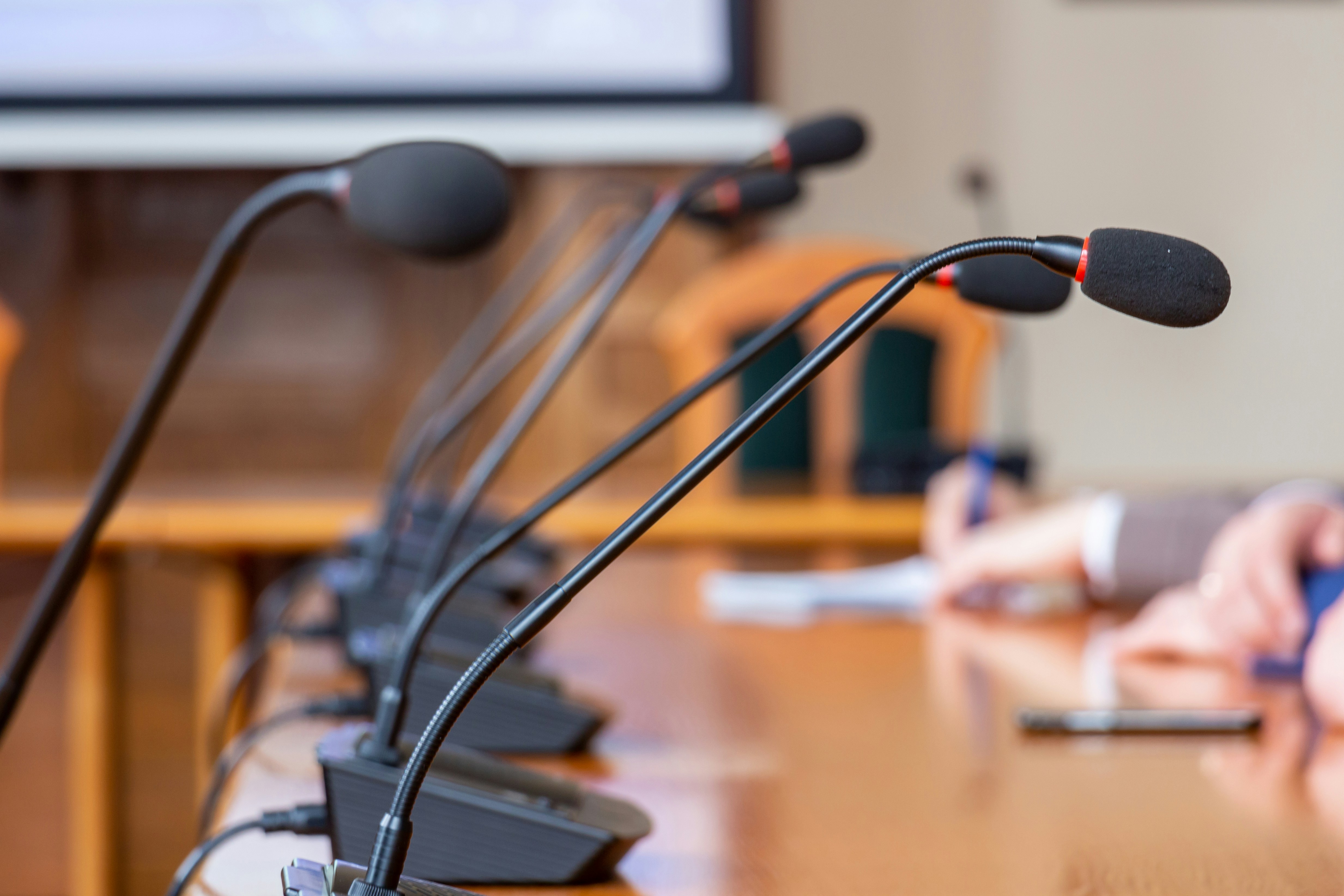 Closeup of microphones at a press conference table.