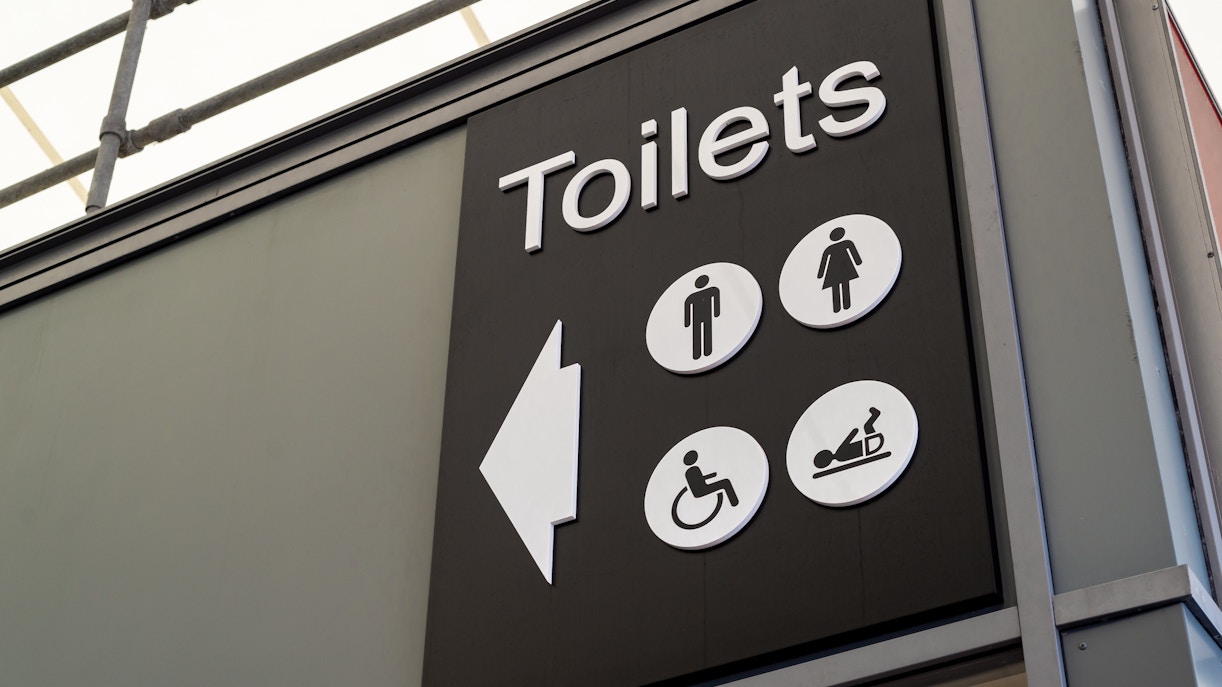 Toilet sign with symbols for men, women, wheelchair access, and baby changing.