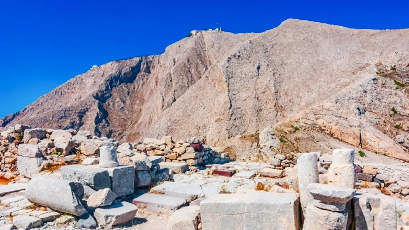 Ruins of Akrotiri archaeological site with mountain backdrop, Santorini.