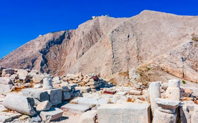 Ruins of Akrotiri archaeological site with mountain backdrop, Santorini.