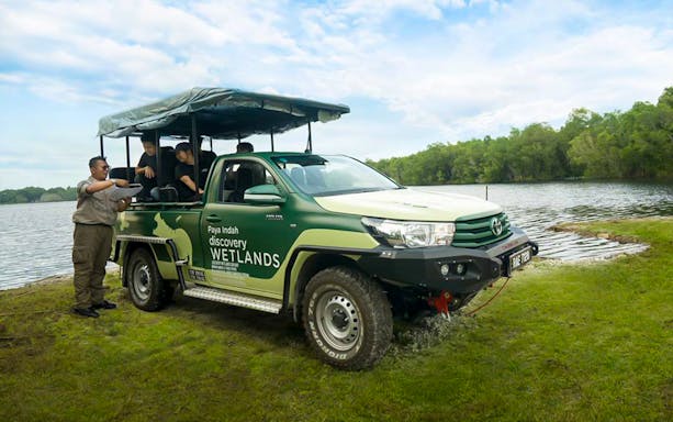 Safari vehicle at Paya Indah Discovery Wetlands, Gamuda Cove, near a lake with guide and tourists.