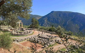 Tholos of Delphi ruins with mountain backdrop at Delphi Archaeological Site, Greece.