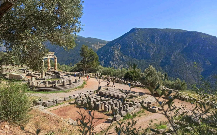 Tholos of Delphi ruins with mountain backdrop at Delphi Archaeological Site, Greece.