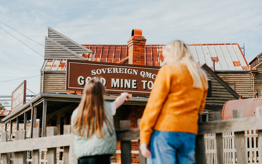 Tourists exploring the Sovereign Hill Gold Mine Tour sign in Ballarat, Australia.