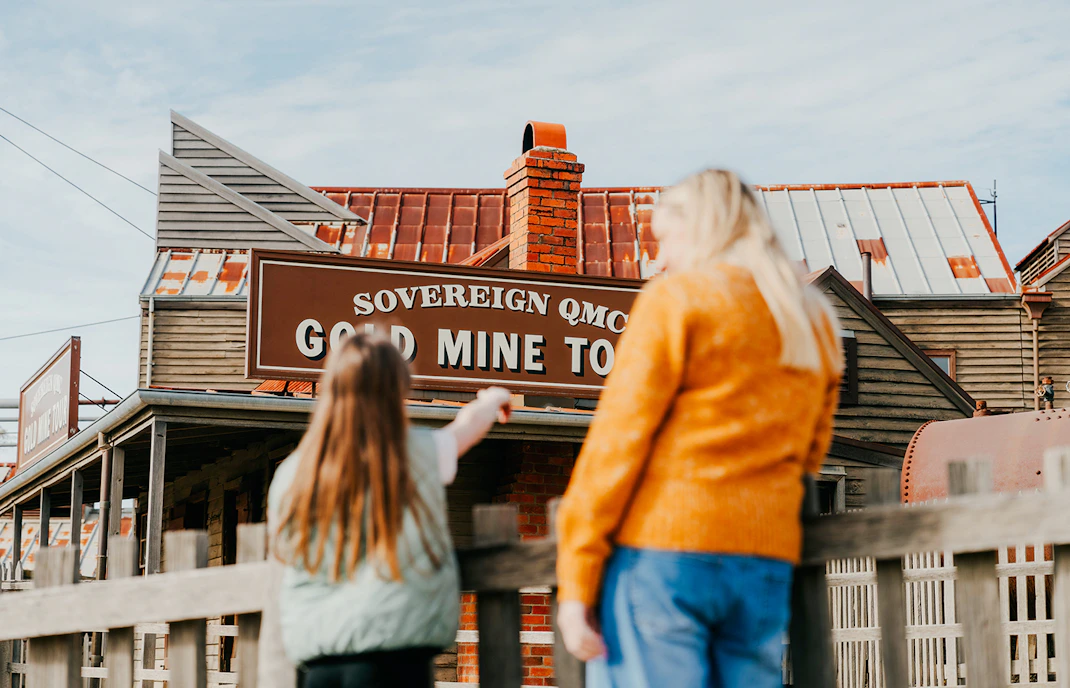 Tourists exploring the Sovereign Hill Gold Mine Tour sign in Ballarat, Australia.